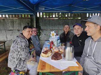 Uczestnicy ŚDS w Gryfinie siedzący przy stole z poczęstunkiem